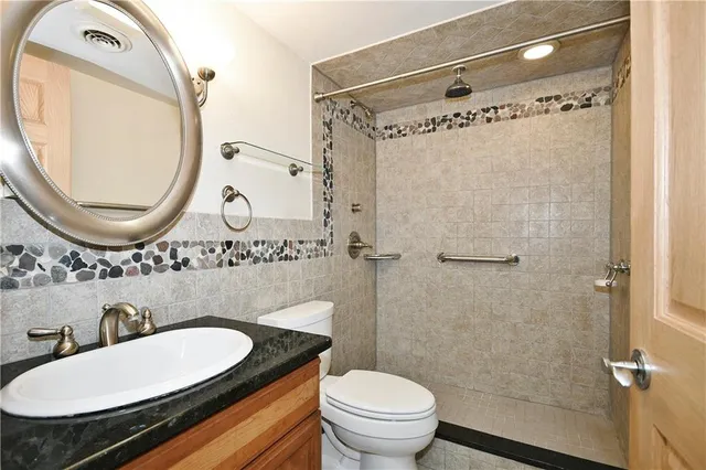 a bathroom with a granite countertop toilet a sink and a mirror