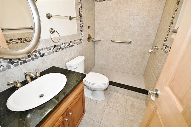a bathroom with a granite countertop sink mirror vanity and toilet