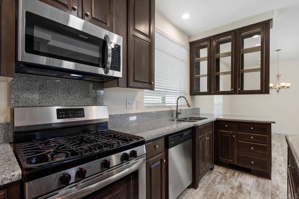 7213 San Luis Street, Unit 171 Carlsbad, CA 92011 - Photo 14 of 44 a kitchen with stainless steel appliances granite countertop a stove and a microwave