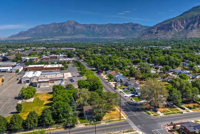 178 17th Street Ogden, UT 84404 - Photo 26 of 29 Expansive aerial perspective showcasing a residential neighborhood with tree-lined streets, a commercial area, and a prominent mountain range backdrop
