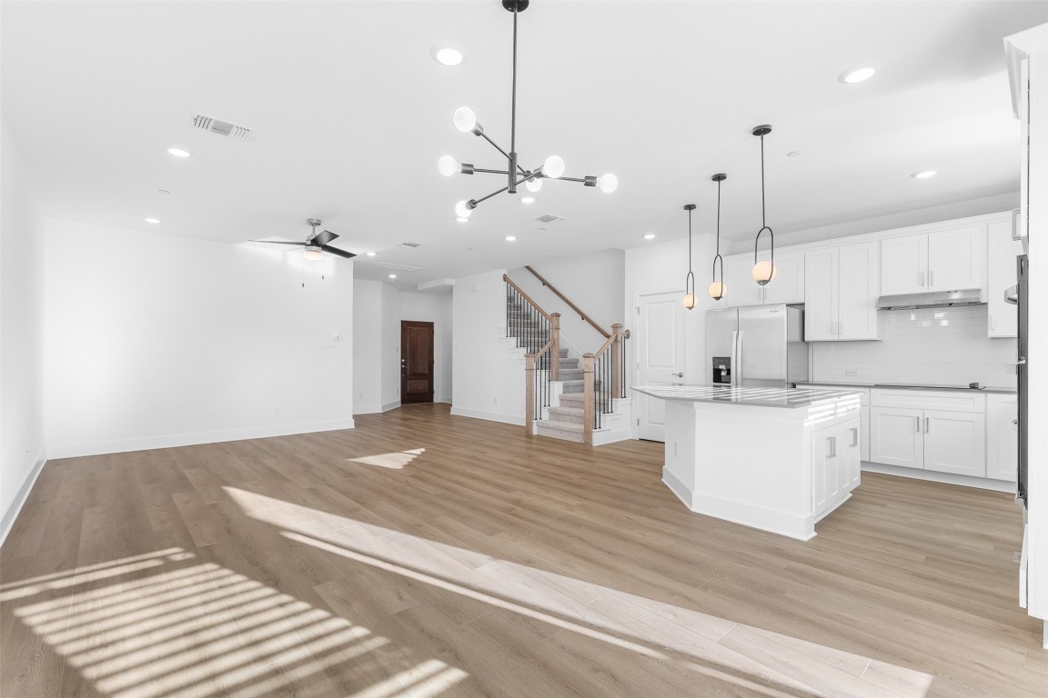 1955 Settlers Glen Drive, Unit 4301 Round Rock, TX 78665 - Photo 19 of 19 a large kitchen with white cabinets and wooden floor