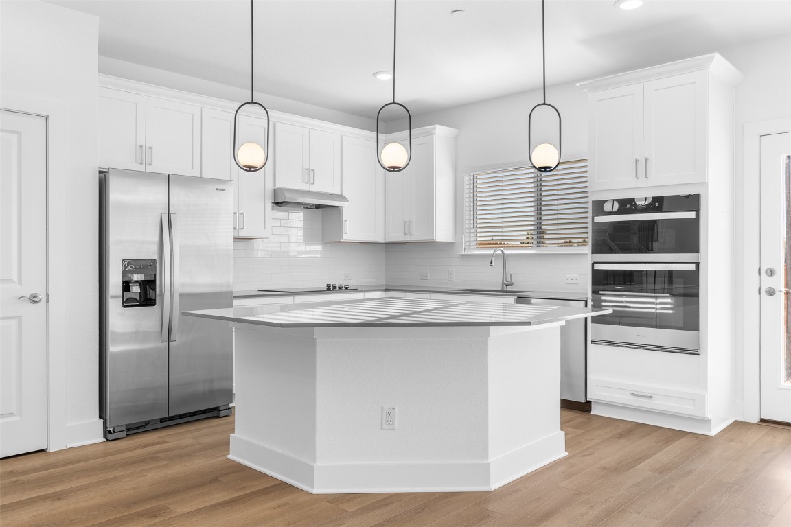 1955 Settlers Glen Drive, Unit 4301 Round Rock, TX 78665 - Photo 4 of 19 a kitchen with stainless steel appliances granite countertop a sink a refrigerator and a wooden floor