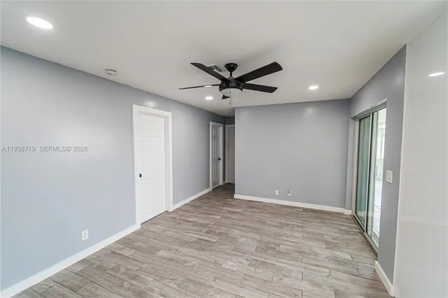 a view of an empty room with a window and wooden floor