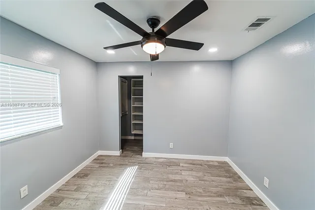 a view of an empty room with window and a ceiling fan