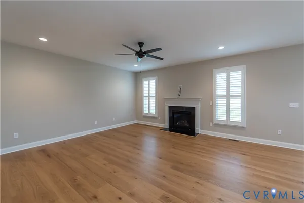 an empty room with windows fireplace and wooden floor