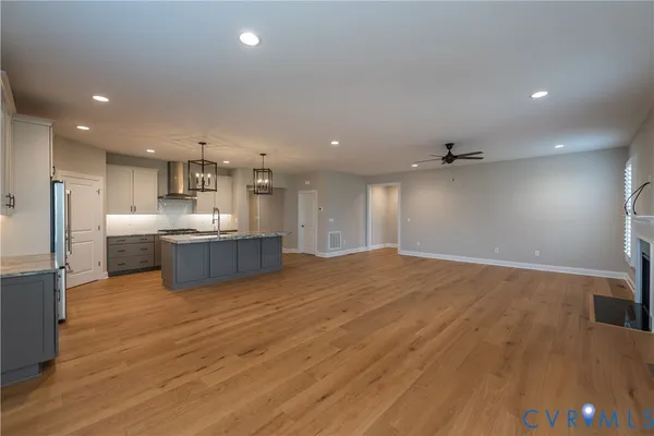 a view of kitchen and empty room with wooden floor