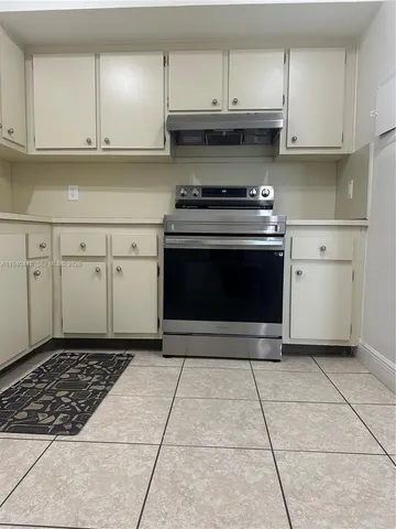 a kitchen with granite countertop a stove a sink and cabinets