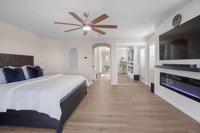 a spacious bedroom with a large bed a flat tv screen and a chandelier