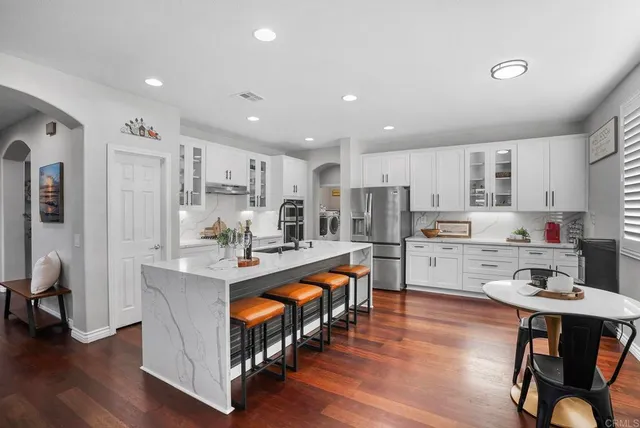a kitchen with stainless steel appliances granite countertop a table chairs refrigerator sink and cabinets