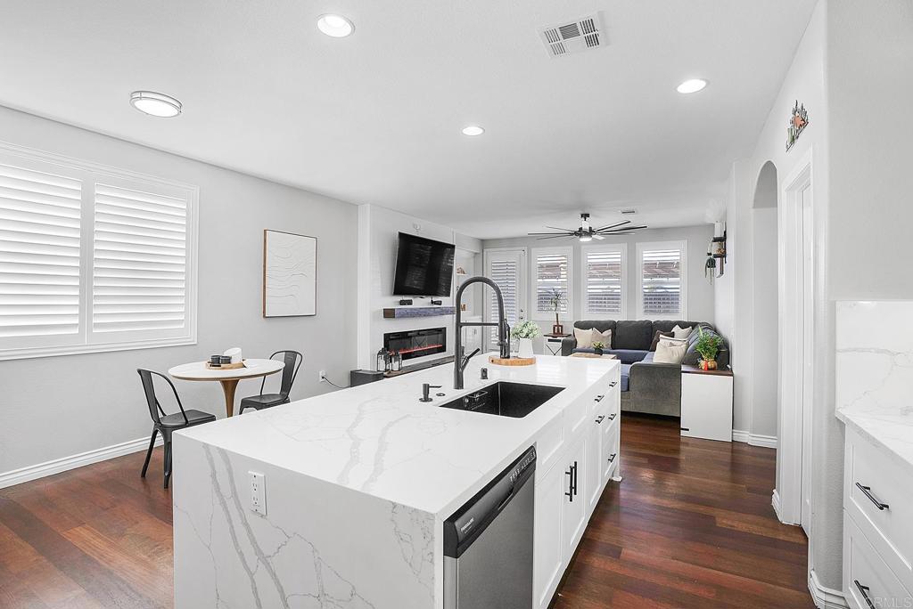 1777 Clover Tree Court Chula Vista, CA 91913 - Photo 9 of 49 a large white kitchen with a white countertops a stove a couch and a dining table with wooden floor