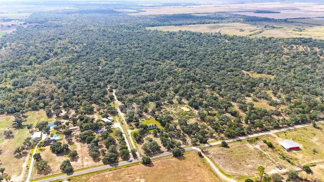 an aerial view of residential house with outdoor space and trees all around