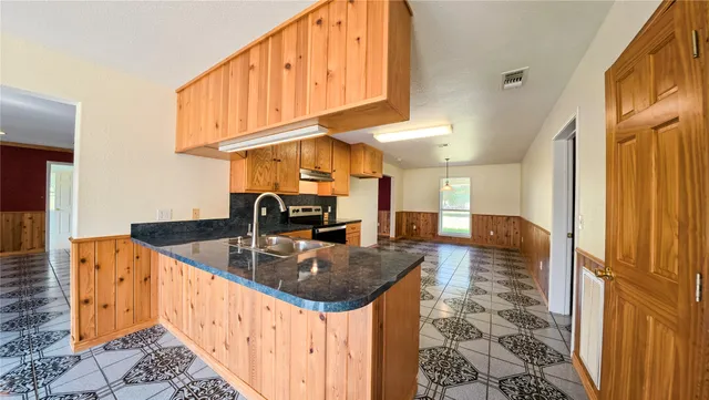 a kitchen with stainless steel appliances granite countertop a stove a sink and a microwave