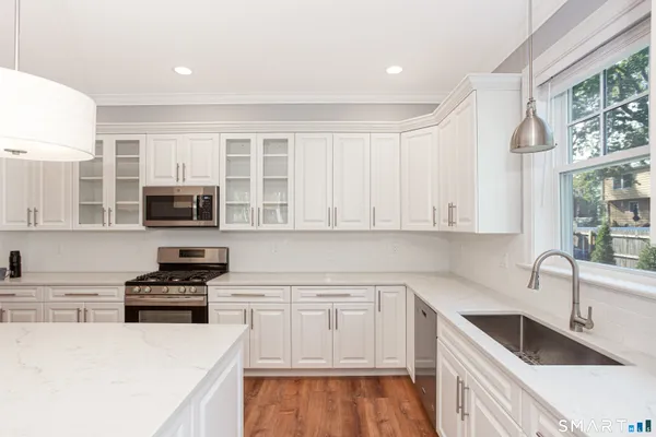 a kitchen with granite countertop a sink a counter top space stainless steel appliances and cabinets