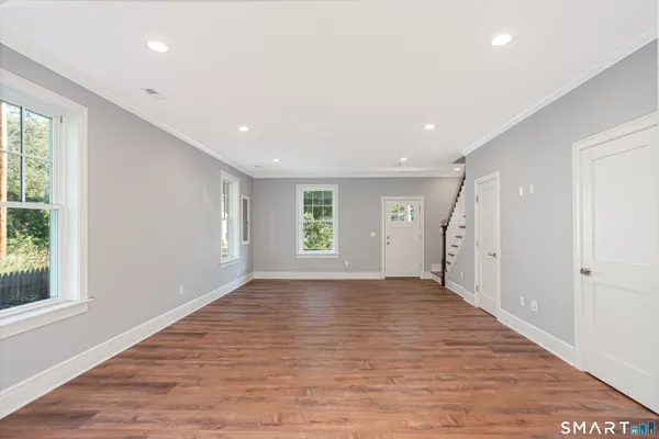 a view of an empty room with wooden floor and a window