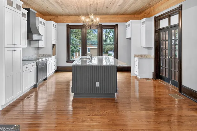 a view of a kitchen with kitchen island granite countertop wooden floor a large window and stainless steel appliances