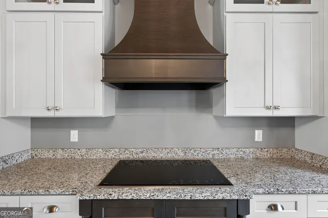 a kitchen with granite countertop white cabinets and a stove