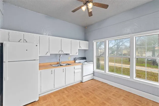 a kitchen with granite countertop a refrigerator a sink a stove and white cabinets