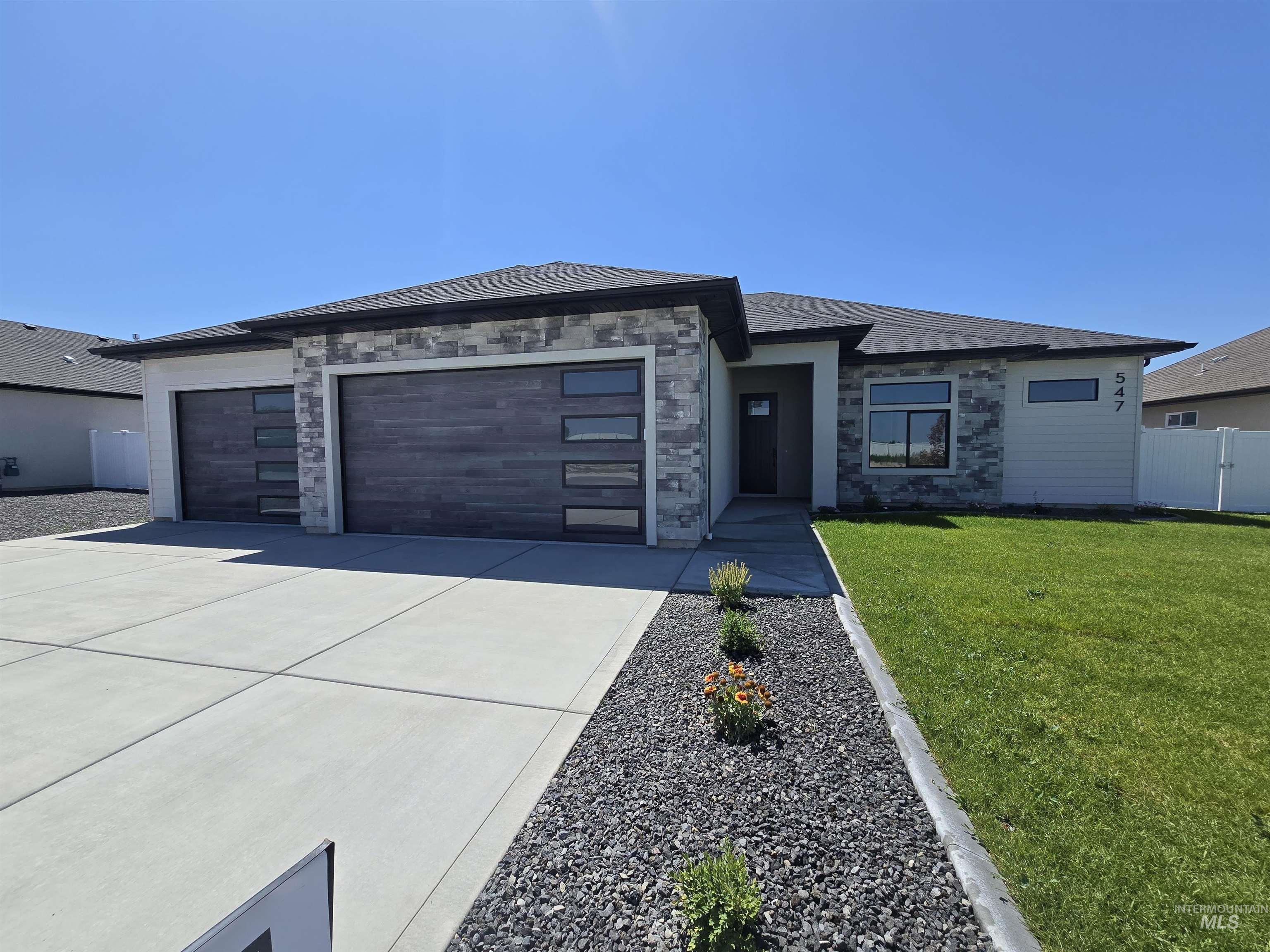 Prairie-style home featuring a garage, driveway, and stone siding