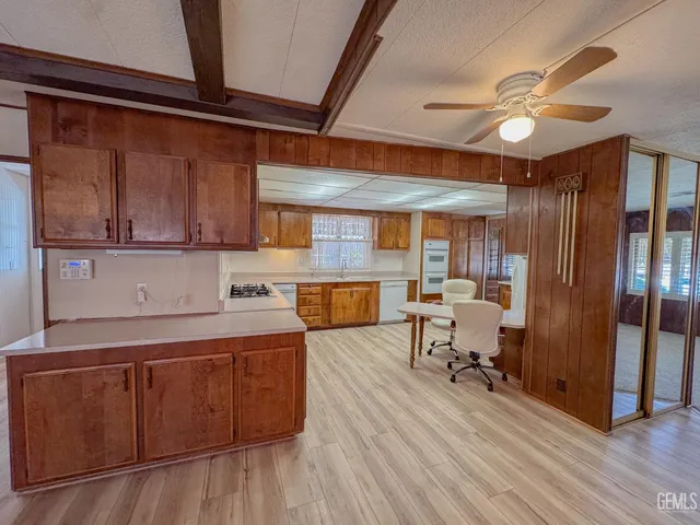 a kitchen with stainless steel appliances granite countertop a refrigerator a sink dishwasher a stove and white countertops with wooden floor