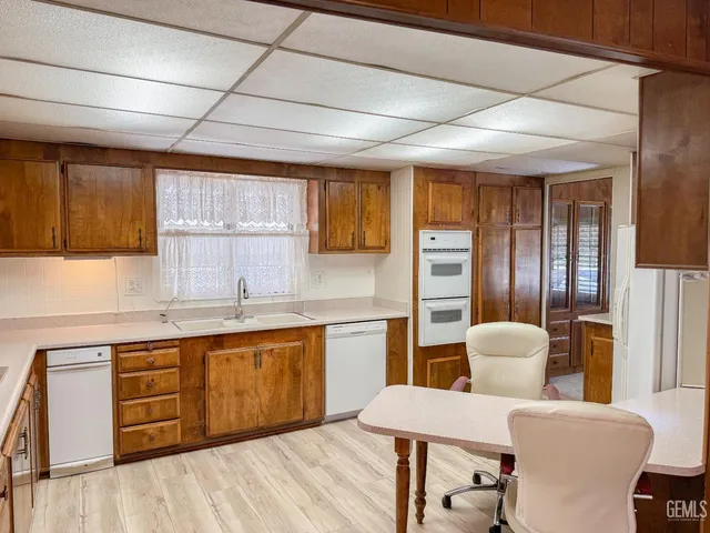 a large kitchen with a table chairs wooden cabinets and stainless steel appliances