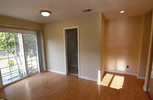 an empty room with wooden floor and windows