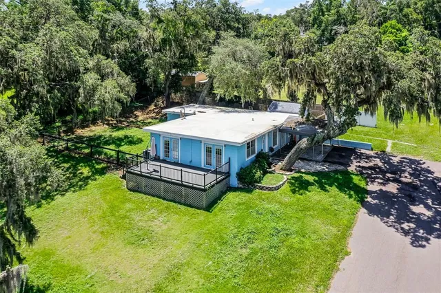 a view of a house with a big yard and large trees
