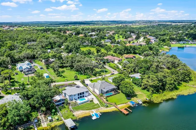 an aerial view of residential houses with outdoor space and trees