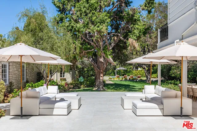 a view of a pool with lawn chairs under an umbrella