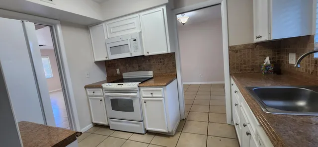a kitchen with white cabinets and white appliances