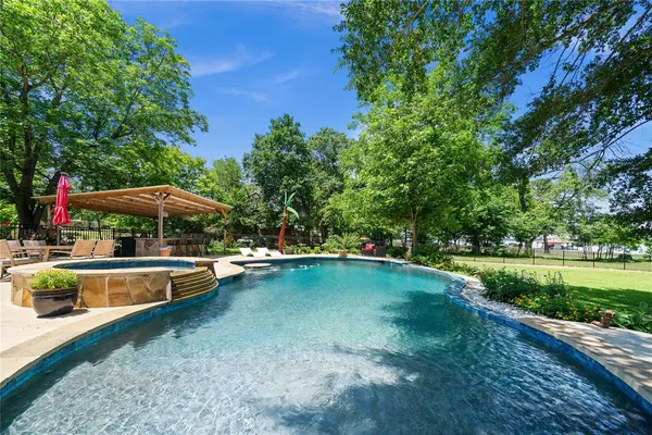 a view of a swimming pool with a table and chairs under an umbrella