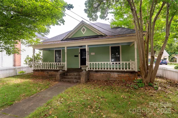 a view of a house with a yard and potted plants and a large tree