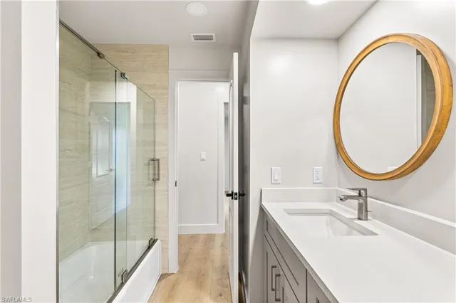 a bathroom with a sink a mirror a vanity and a shower