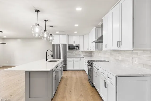 a large kitchen with stainless steel appliances granite countertop a sink and dishwasher a stove with wooden floor