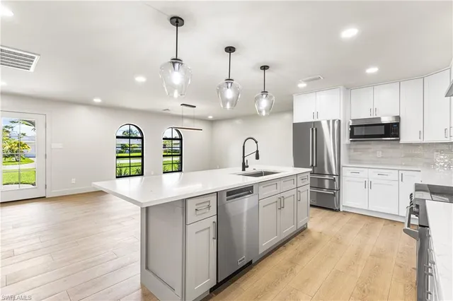 a kitchen with stainless steel appliances granite countertop a sink a stove and a wooden floors