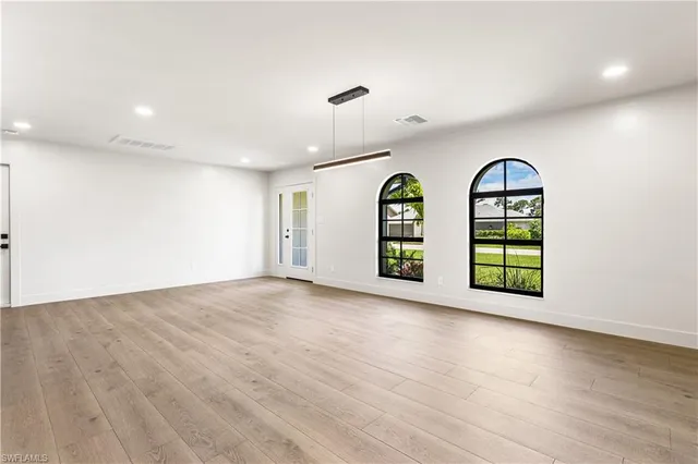 an empty room with wooden floor windows and glass door