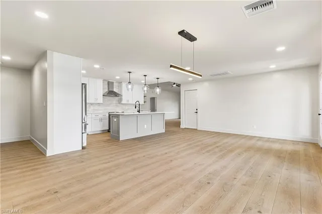 a view of a kitchen with kitchen island a sink wooden floor and stainless steel appliances