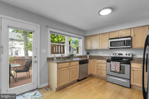 a kitchen with stainless steel appliances granite countertop a stove top oven a sink and a granite counter tops with white cabinets