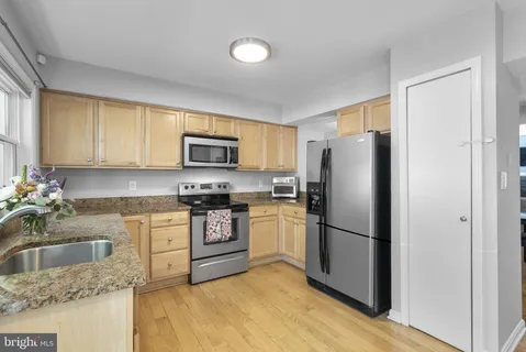 a kitchen with stainless steel appliances granite countertop a refrigerator stove top oven and sink