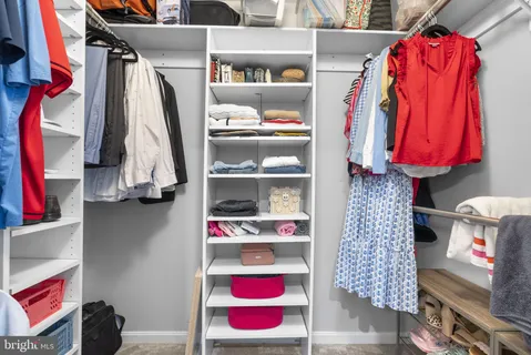 a view of walk in closet with clothes and shoes