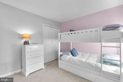 a bedroom with a white bed and dresser with mirror