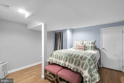 a bedroom with a bed a dresser and wooden floor