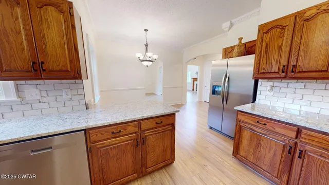 a kitchen with stainless steel appliances granite countertop wooden cabinets a refrigerator and a sink