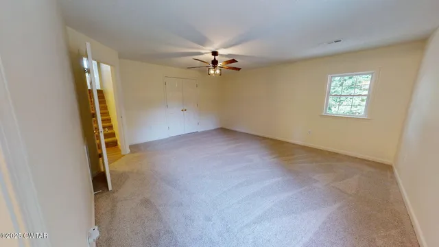 an empty room with windows and fan