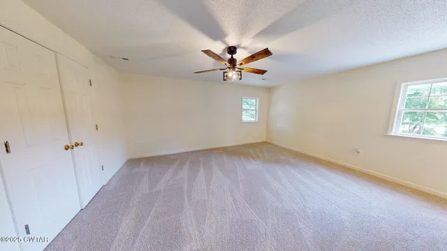 an empty room with a window and a fan
