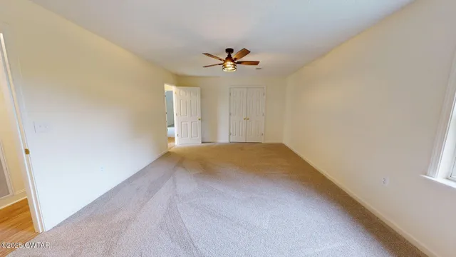an empty room with windows and fan