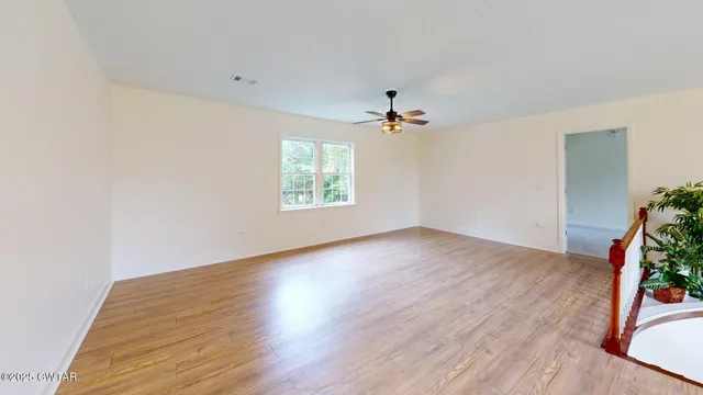 an empty room with wooden floor and natural light