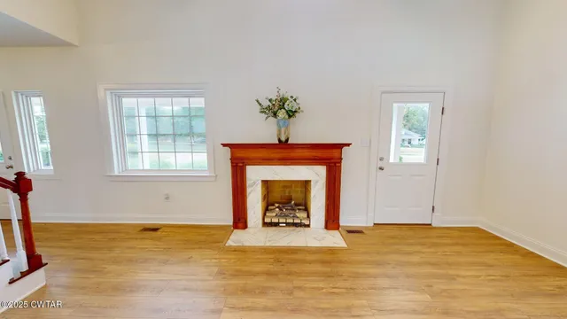 a view of an empty room with window and fireplace