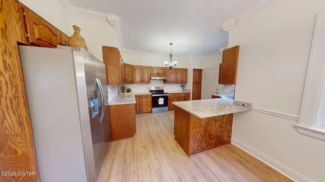 a kitchen with stainless steel appliances granite countertop a refrigerator a stove a sink dishwasher and a oven with wooden floor