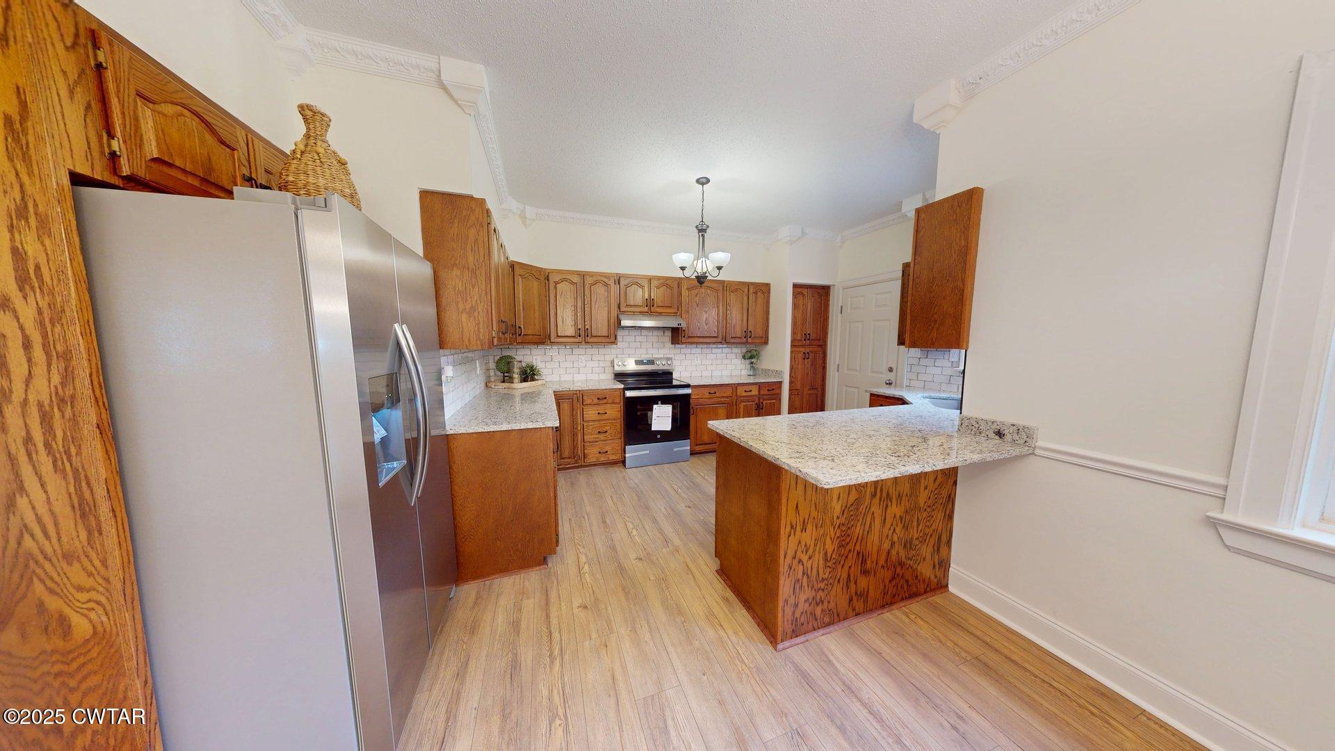 404 West Main Street Newbern, TN 38059 - Photo 9 of 35 a kitchen with stainless steel appliances granite countertop a refrigerator a stove a sink dishwasher and a oven with wooden floor