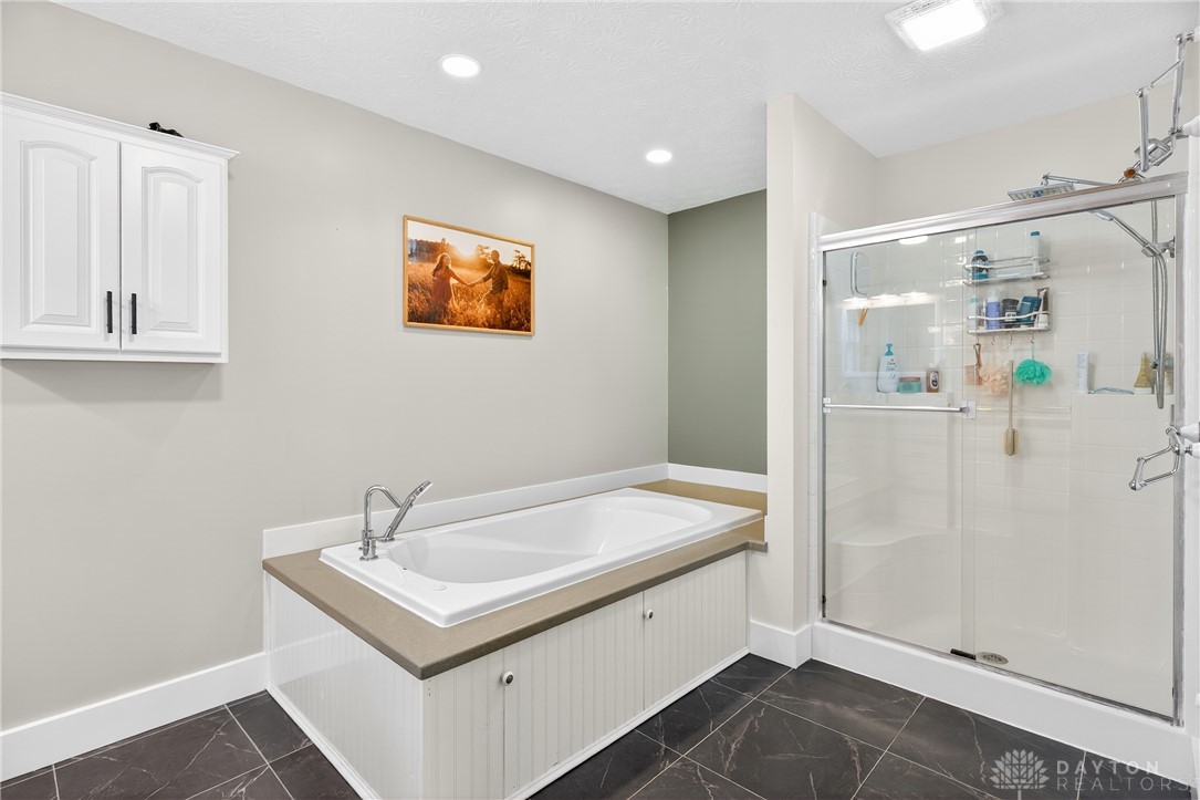 7888 Darke-Preble County Line Road Arcanum, OH 45304 - Photo 28 of 51 This serene bathroom offers a spacious soaking tub and a sleek, glass-enclosed shower.